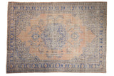 Distressed Turkish Oushak rug, blue floral medallion on a pale sandalwood field.