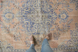 Worn texture of a distressed Turkish Oushak carpet with pale sandalwood and blue rococo florals.