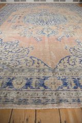 Distressed Oushak rug with faded pale sandalwood and vibrant denim blue floral motifs.