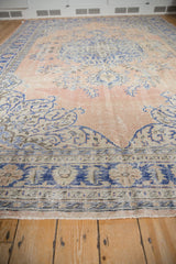 Vintage distressed Oushak carpet with worn texture in pale sandalwood and blue tones.