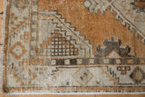 Oushak runner corner with copper field, geometric border, and worn pile showing foundation.
