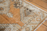 Distressed vintage Oushak runner corner, featuring copper and beige geometric patterns and fringe.
