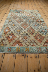 Vintage distressed Tulu rug, showing textured lattice pattern with faded orange, blue, and ivory tones.