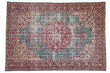 Vintage distressed Sivas carpet with a cherry red medallion on a faded ocean blue field with floral details.