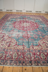 Angled view of a vintage Sivas rug with a worn texture and cherry red medallion on a blue field.