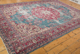 Angled view of a distressed Sivas carpet with a red medallion and time-softened blue field.