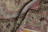 Distressed vintage Oushak runner close-up, showing mauve, brown, and violet geometric patterns.