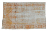 Vintage distressed Oushak rug with a faded floral medallion in antique ivory, beige, and saffron yellow.