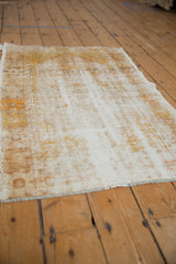 Angled view showing the distressed, low-pile texture and exposed ivory foundation of a vintage Oushak rug.