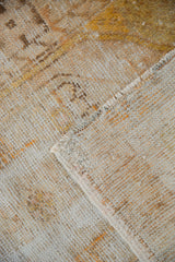 Folded corner showing the hand-knotted foundation and worn pile of a distressed Oushak rug.