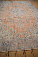 Distressed vintage Oushak rug with visible pile wear, showing faded terracotta and royal blue.