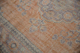 Distressed Oushak rug pile with worn texture, featuring faded terracotta and royal blue.