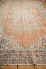 Distressed Oushak rug corner, with worn rust orange field and blue floral corner spandrel.