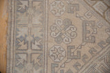 Close-up of a Turkish Melas rug pile, displaying distressed ivory and beige geometric patterns and side selvage.