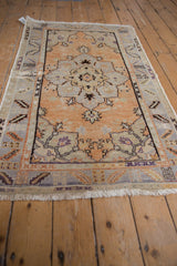 Worn corner of distressed vintage Oushak rug, pale tangerine field, playful plant border.