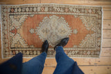 Distressed corner of a vintage Oushak rug, showing even wear, dusty rust, and patterned beige border.