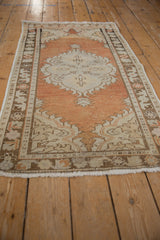 Distressed Oushak rug runner's abrashed orange field, beige medallion, and worn pile.
