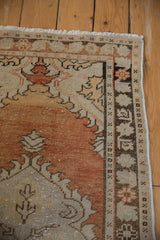 Corner of distressed Oushak runner with fringe, intact selvage, and worn pile in rust and sand.