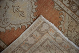 Vintage Oushak rug's hand-knotted reverse, revealing tight weave, fringe, and secured side cord.