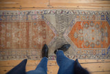 Distressed Oushak runner's central intersection with faded orange, beige, and blue medallions.