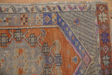 Distressed Oushak runner corner, showing rust, blue, grey checkered patterns and worn texture.