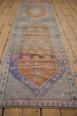 Distressed Oushak runner edge showing faded blue, pink, and rust motifs.