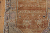 Textured pile of distressed Oushak runner, showing worn rust and a serrated border.