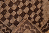 Vintage Oushak rug's decorative checkered brown and beige pile with visible selvage.