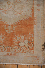 Distressed vintage Oushak rug detail: faded tangerine floral motifs, light field, and wear.