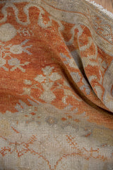Distressed vintage Oushak rug pile with visible knot heads and faded tangerine orange.