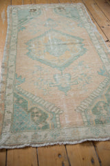 Angled view of a vintage Oushak rug showing its time-softened pile and muted seafoam pattern.