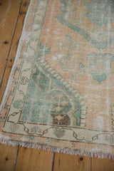 The lattice corner spandrel and meandering vine border of a distressed vintage Oushak rug.