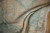 Detailed texture of a vintage Oushak rug showing wear to the knot heads in seafoam and gold tones.