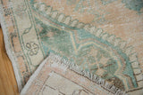 Corner of a distressed Oushak rug showing the hand-knotted back and evenly worn low pile.