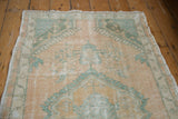 The distressed end of a vintage Turkish Oushak rug with a seafoam and gold border pattern.