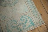 Distressed Oushak rug corner with pale turquoise border, showing mostly even wear and intact side cord selvage.