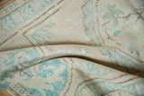 Distressed ivory and pale turquoise Oushak rug with low pile texture.