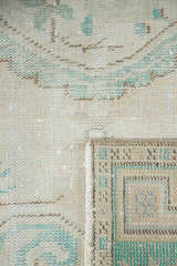 Distressed Oushak runner pile with mostly even wear, pale ivory, turquoise, and visible folded selvage.