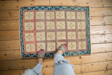 Vintage distressed Oushak rug shows worn multi-paneled motifs and indigo vine border.