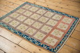 Distressed vintage Oushak rug corner with indigo meandering vine border and soft texture.