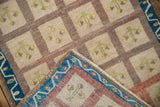 Vintage Oushak rug corner showing vibrant indigo border, ivory fringe, and distressed paneled field.