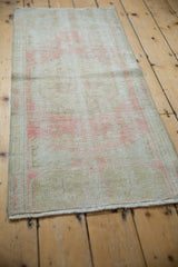 Distressed vintage Oushak runner with faded rose and beige traditional floral pattern.