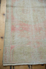 Distressed Oushak runner's worn rose-beige pile, showing foundation, and intact side selvage.