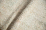Varied hand-knotted pile texture of the distressed Oushak rug, featuring ivory, beige, and faint green hues.