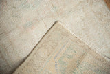 Distressed pile of vintage Oushak rug with visible foundation and hand-knotted back.