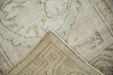 Distressed vintage Oushak rug texture revealing faint foundation, woven reverse, and side selvage.