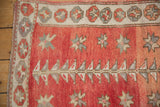 Vintage Oushak rug corner, dusty rose field with geometric plants, starbursts, and ivory pomegranate border.
