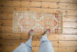 Distressed vintage Oushak mat runner with faded terracotta medallions on ivory, worn pile.