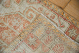 Folded corner of vintage Oushak rug revealing distressed pile and hand-knotted foundation.