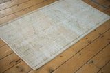 Vintage distressed Oushak rug corner showing worn pile texture and intact selvage.